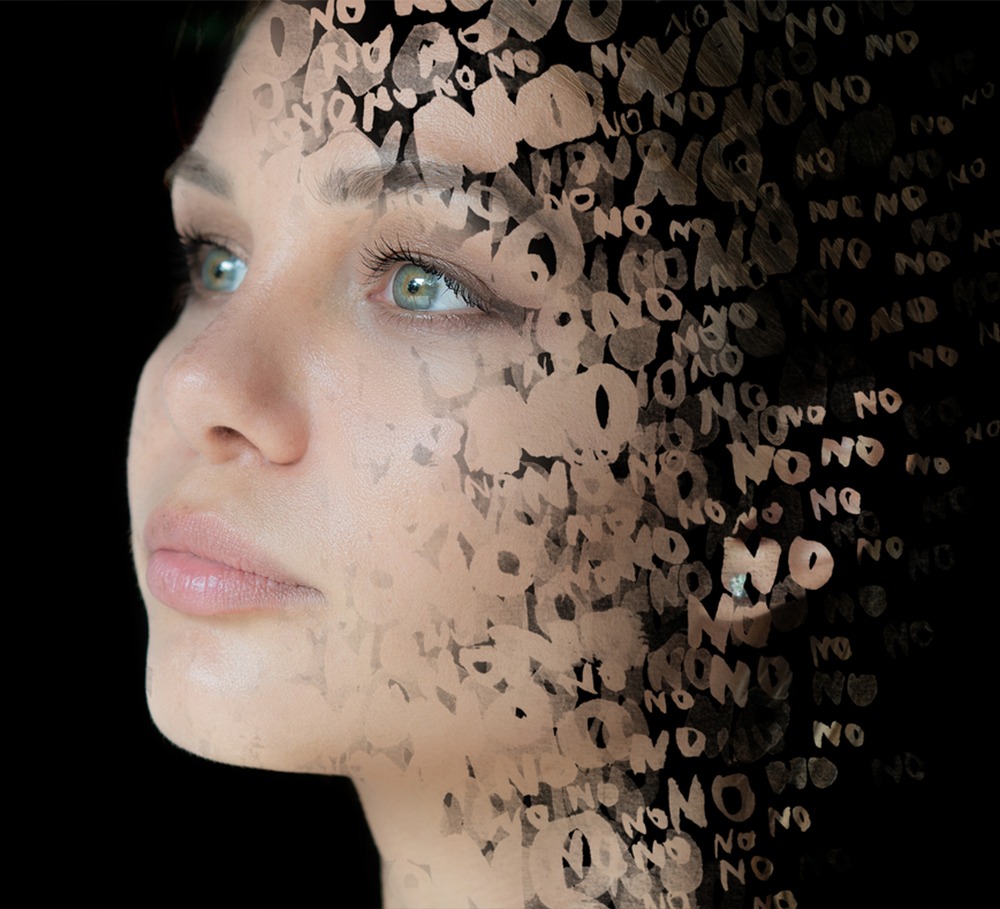 A close-up of a woman's face with her features partially obscured by translucent text saying "NO," suggesting themes of rejection or resistance.